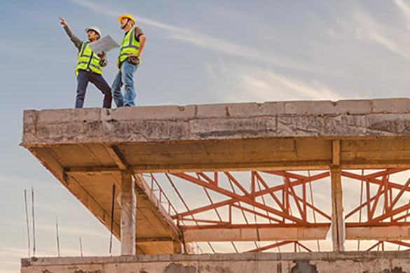 two construction workers looking over a project plan while on a busy worksite