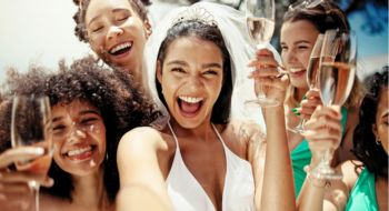 a bride and her bridesmaids holding champagne glasses and smiling for the camera